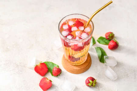 Glass of tasty strawberry cocktail mojito on light background