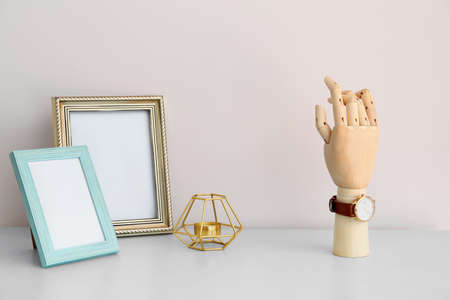 Wooden hand with wristwatch, candle and photo frames on table