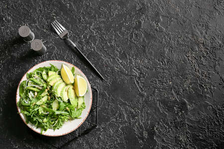 Plate with tasty arugula salad on dark backgroundの写真素材