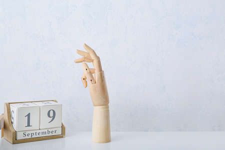Wooden hand with calendar on light backgroundの写真素材