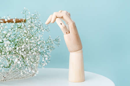 Wooden hand and flowers on color backgroundの写真素材