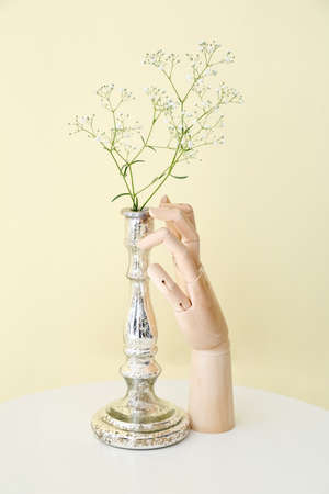 Wooden hand and vase with flowers on tableの写真素材
