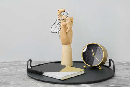 Wooden hand with glasses and clock on tableの写真素材