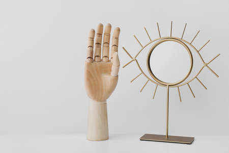 Wooden hand with mirror on light background