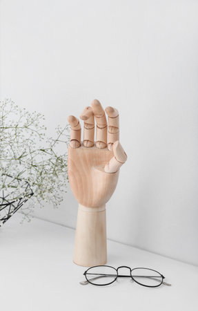 Wooden hand with glasses and flowers on tableの写真素材