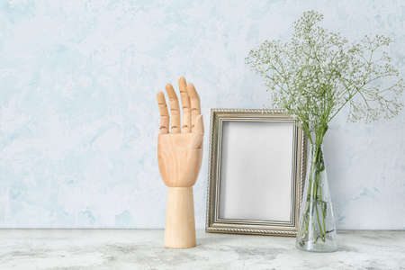 Wooden hand with photo frame and flowers on tableの写真素材