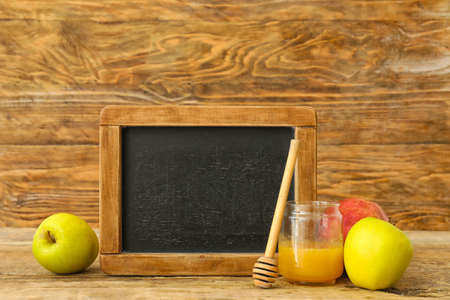 Empty chalkboard with fruits and honey on wooden background. Rosh Hashanah (Jewish New Year) celebrationの写真素材