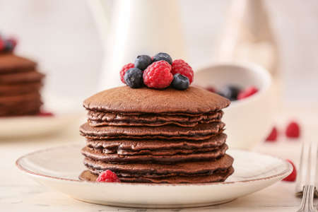 Plate with delicious chocolate pancakes and berries on tableの写真素材