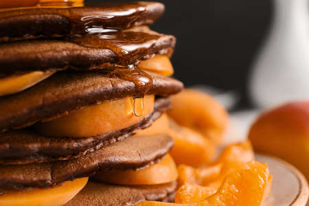 Plate with delicious chocolate pancakes and apricot, closeup