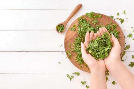 Female hands with dry parsley on wooden backgroundの写真素材