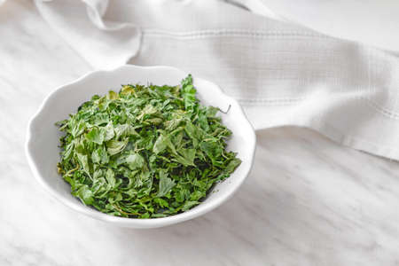 Bowl with dry parsley on tableの写真素材