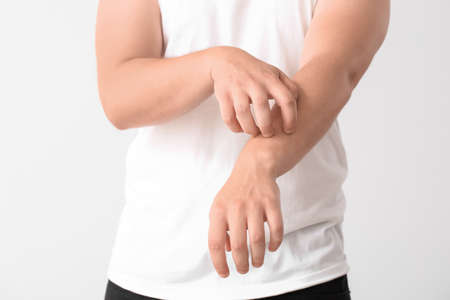 Teenage boy suffering from itching on light backgroundの写真素材