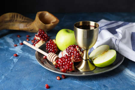 Sacramental goblet with wine, apple and pomegranate on color background. Rosh Hashanah (Jewish New Year) celebrationの写真素材