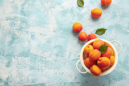 Colander with tasty ripe apricots on color backgroundの写真素材