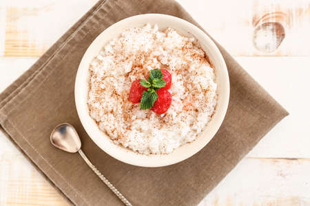 Bowl of tasty rice pudding with cherry on napkinの写真素材