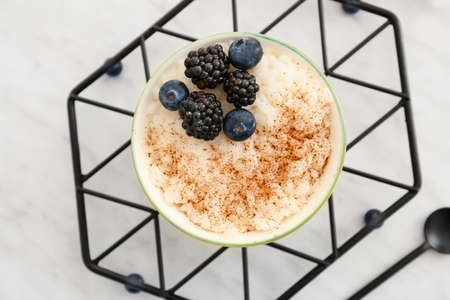 Bowl of tasty rice pudding with berries on white tableの写真素材