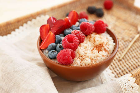 Bowl of tasty rice pudding with berries on wicker trayの写真素材