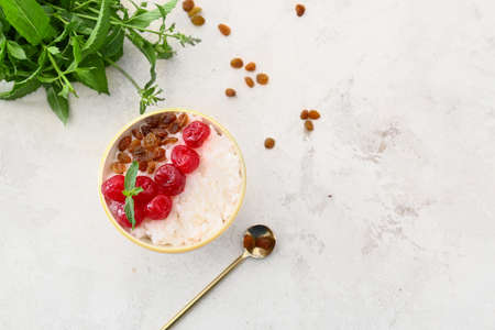 Bowl of tasty rice pudding with raspberry and raisins on white tableの写真素材