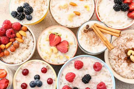 Bowls of tasty rice pudding with berries on light tableの写真素材