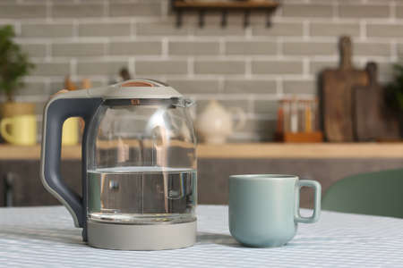 Electric kettle with cup on kitchen tableの写真素材