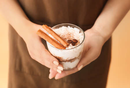 Woman holding glass of tasty rice pudding with cinnamon on light backgroundの写真素材