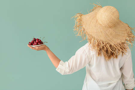 Woman with sweet cherry on color backgroundの写真素材