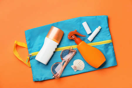 Bag with sunscreen cream and sunglasses on color backgroundの写真素材