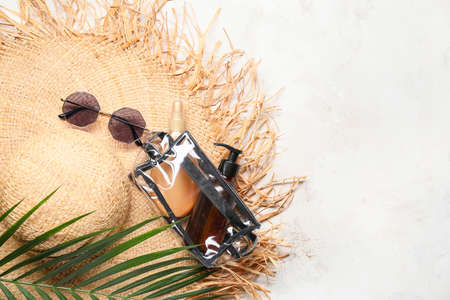 Bag with sunscreen cream, sunglasses and hat on light backgroundの写真素材