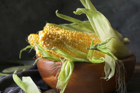 Bowl with fresh corn cobs on table, closeupの写真素材