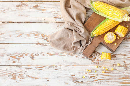 Board with fresh corn cobs on table