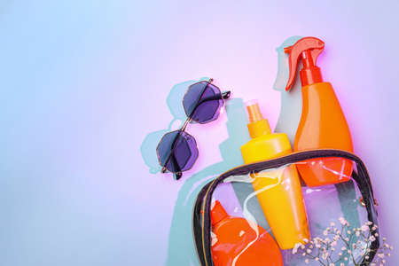 Bag with sunscreen cream and sunglasses on color backgroundの写真素材