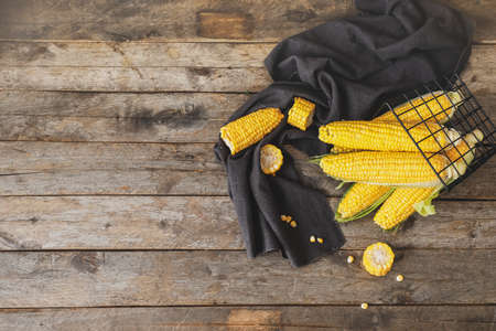 Basket with fresh corn cobs on wooden tableの写真素材