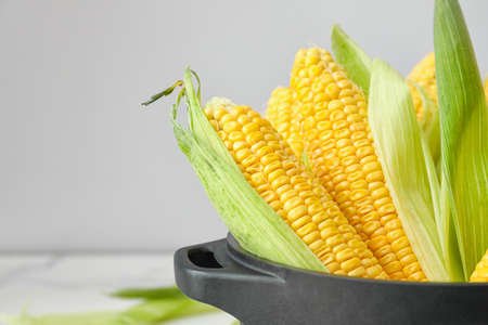 Pot with fresh corn cobs on table, closeupの写真素材