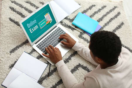 African-American with laptop passing exams online at home