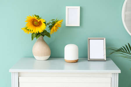 Photo frames with flowers on chest of drawers in roomの写真素材