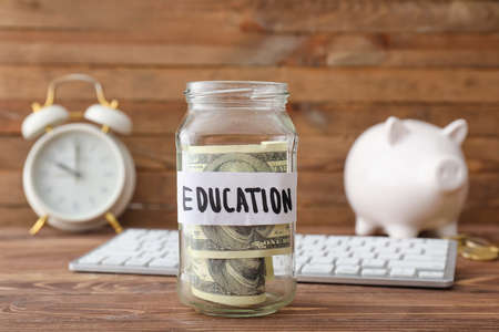Jar with money for education on wooden background. Tuition fees concept