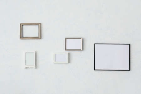 Empty photo frames hanging on wall in roomの写真素材