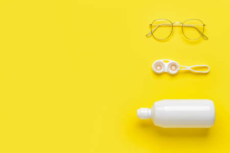 Container with contact lenses, solution tweezers and eyeglasses on color backgroundの写真素材