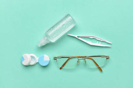 Container with contact lenses, solution, tweezers and eyeglasses on color backgroundの写真素材