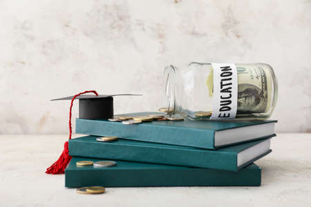 Books, jar with money and graduation hat on table. Tuition fees conceptの写真素材