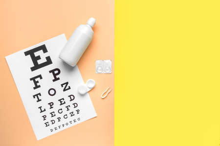 Container with contact lenses, tweezers, solution and eye test chart on color backgroundの写真素材