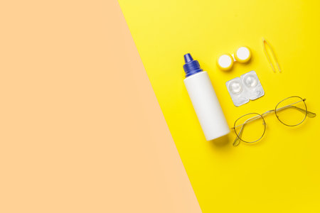 Container with contact lenses, solution, tweezers and eyeglasses on color backgroundの写真素材