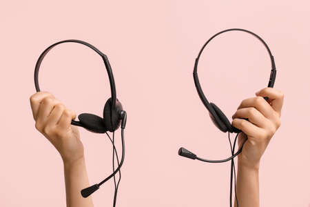 Female hands with headset on color backgroundの写真素材
