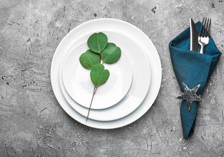 Simple table setting with eucalyptus on dark background