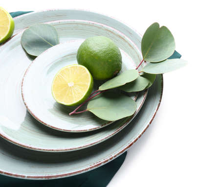 Beautiful table setting with lime and eucalyptus on white background