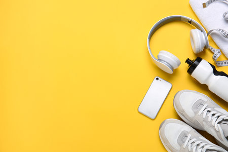 Sportive shoes, bottle of water, mobile phone, measuring tape and headphones on color backgroundの写真素材