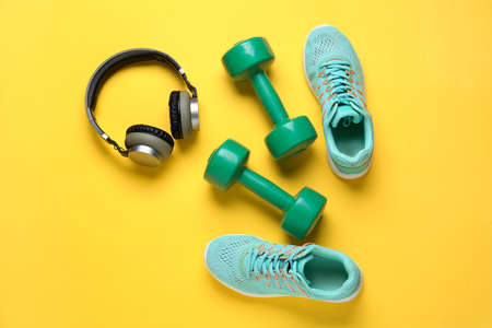 Sportive shoes, dumbbells and headphones on color backgroundの写真素材
