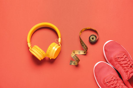 Sportive shoes, measuring tape and headphones on color backgroundの写真素材