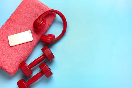 Dumbbells, towel, mobile phone and headphones on color backgroundの写真素材