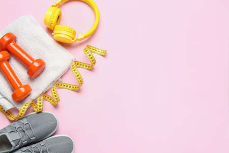 Sportive shoes, dumbbells, towel, measuring tape and headphones on color backgroundの写真素材